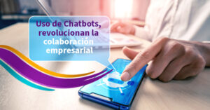 ejecutivo trabajando en su escritorio, mano señalando pantalla de telefono donde se visualiza el bot, chatbot, mano contraria recargada sobre laptop, fondo oficina, luz calida